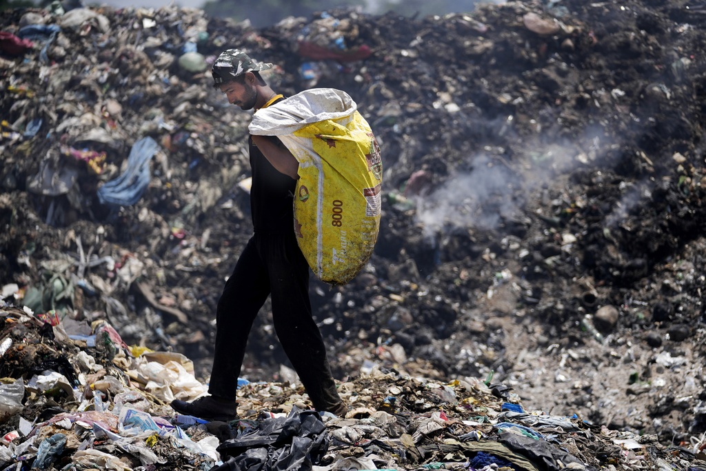 Aamir Shekh looks for recyclable material at a garbage dump