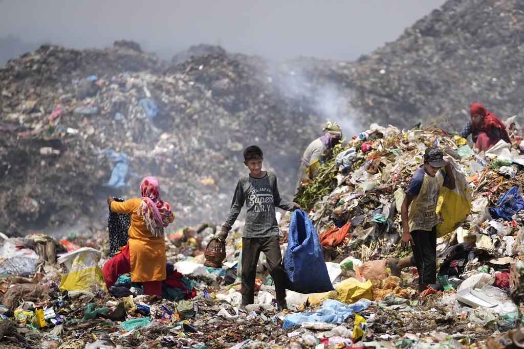 Waste picker Rajdin, 17, looks for recyclable material during a heat wave at a garbage dump on outskirts of Jammu
