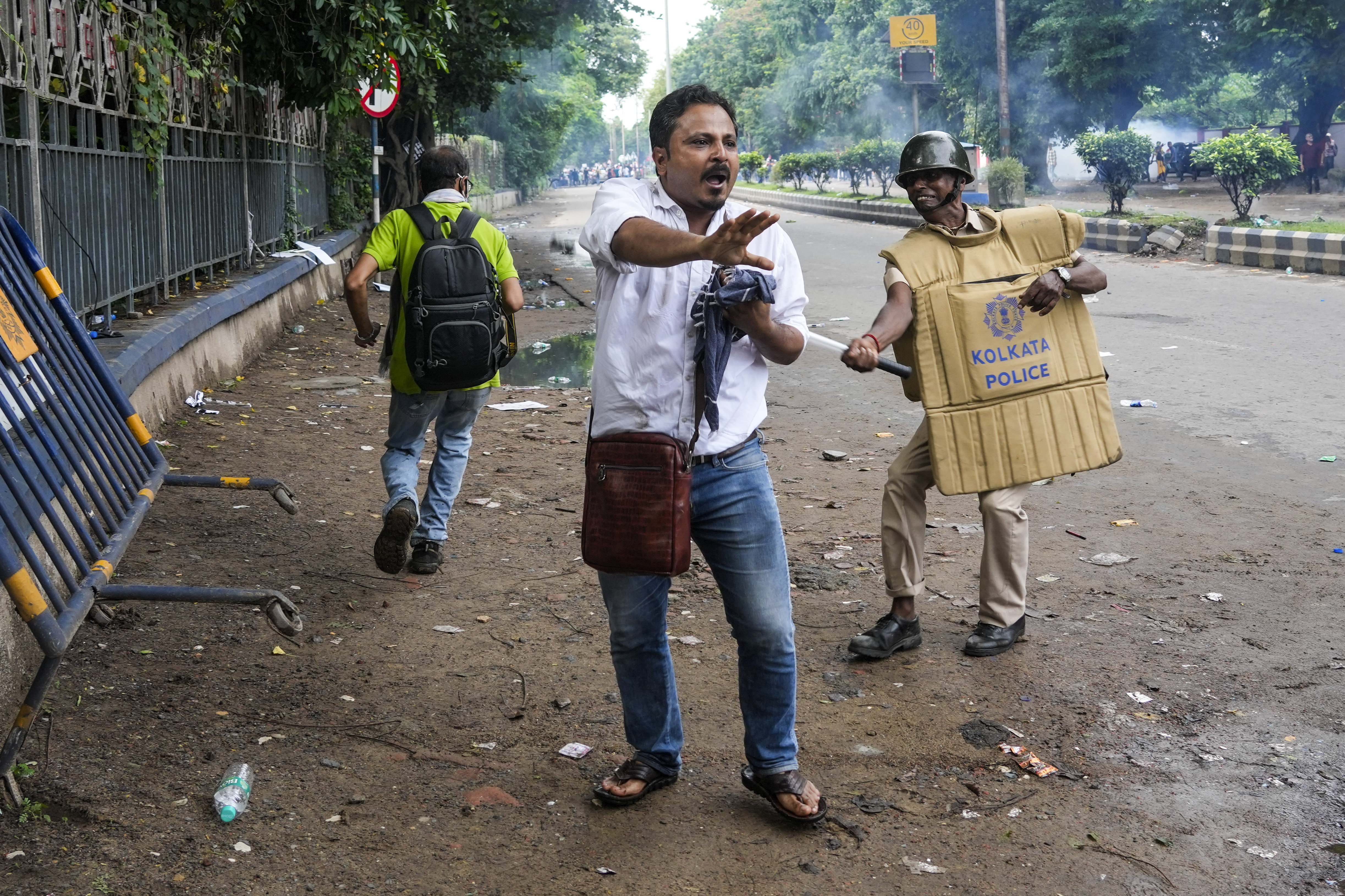 Protestors against the rape and murder of a resident doctor at a government hospital earlier this month, run from police firing tear gas, in Kolkata,