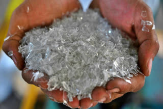 This picture taken on August 5, 2022 shows a worker with shards of processed plastic material at a plastics recycling factory in Indonesia's Banten province.