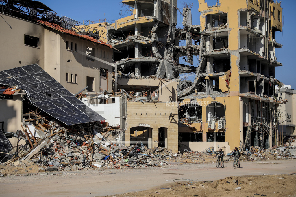 Palestinians ride bicycles by destroyed buildings in Gaza City