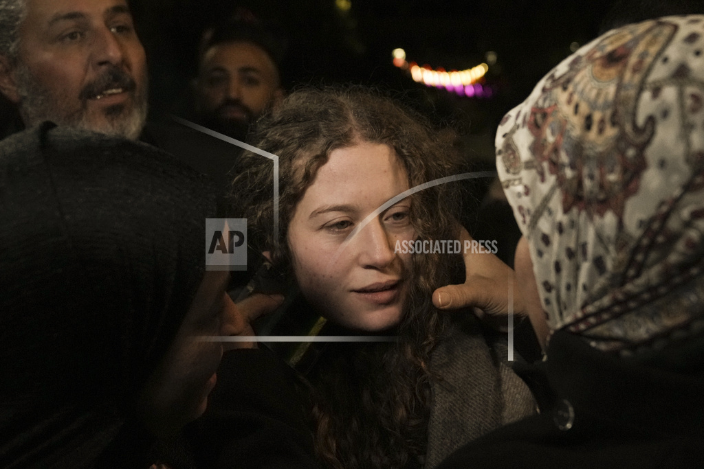 Palestinian activist Ahed Tamimi, center is hugged by a woman after she was released from prison by Israel