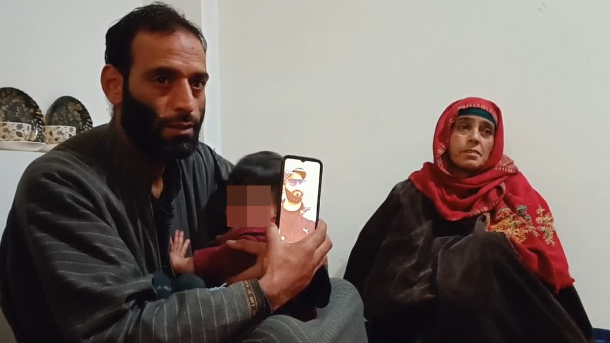 Wasim Ahmad (L) brother of BJP worker killed in J-K militant attack shows the picture of his slain brother in Shopian, Jammu and Kashmir