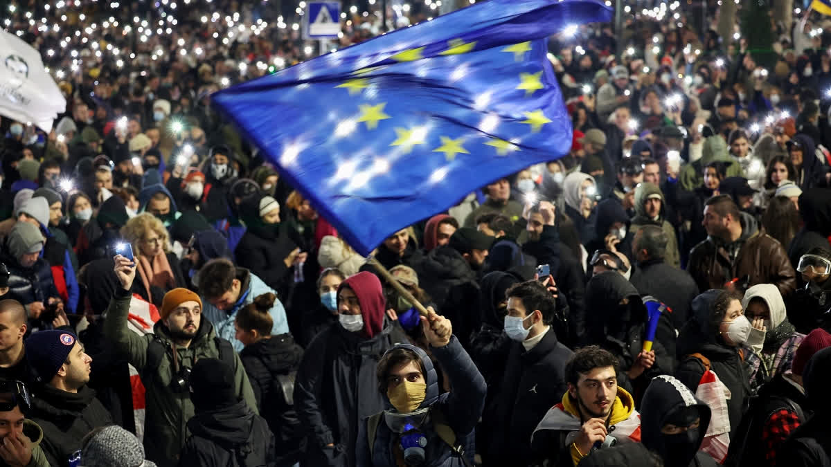 A man waves an European Union flag as demonstrators gather to protest near the Parliament building in opposition to the government's decision to delay European Union (EU) accession negotiations until 2028 in downtown Tbilisi on November 29, 2024.