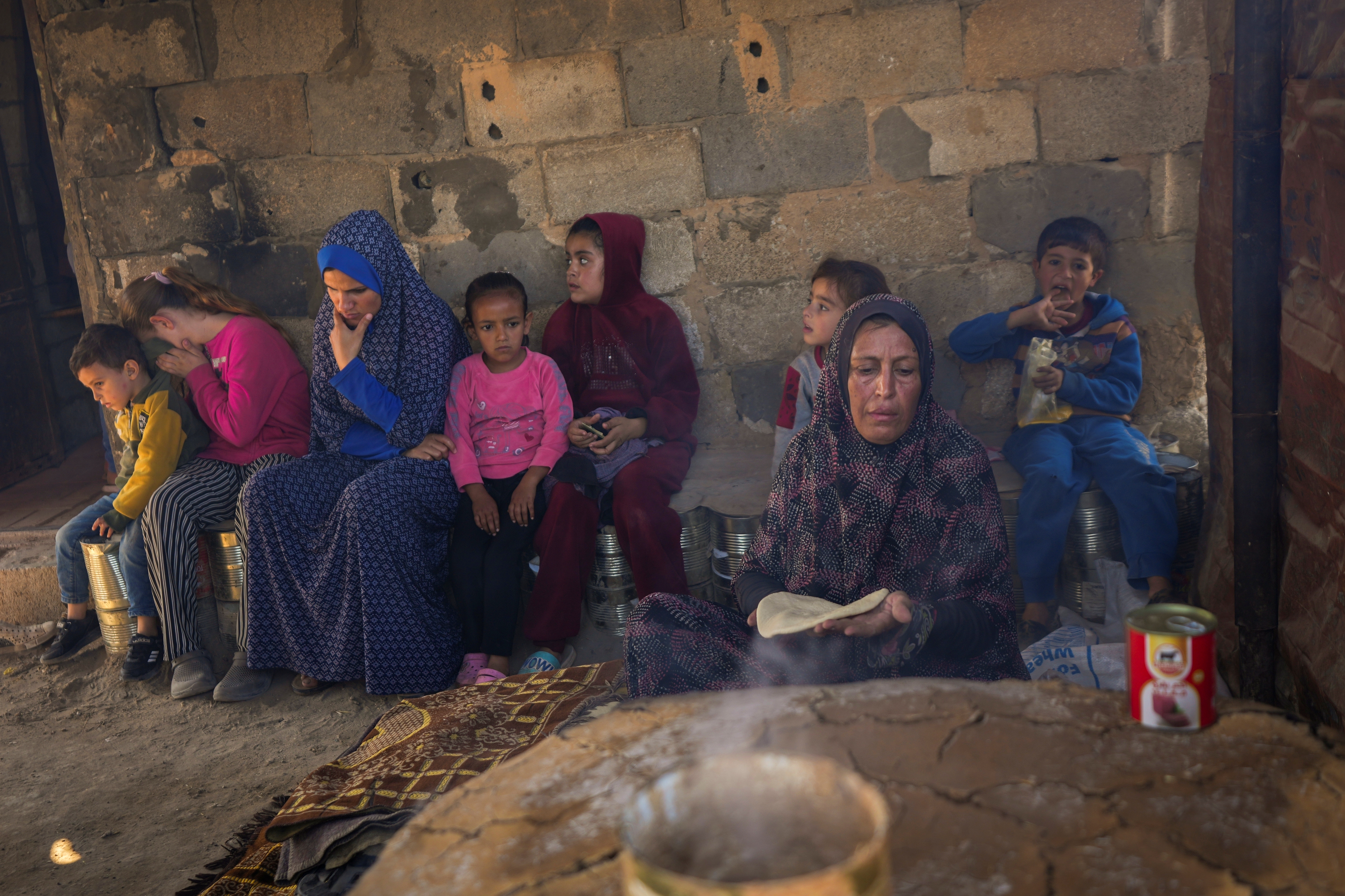 Amal Al-Jali, a 46-year-old mother of 14 displaced from Gaza City, prepares bread at a camp for displaced Palestinians.