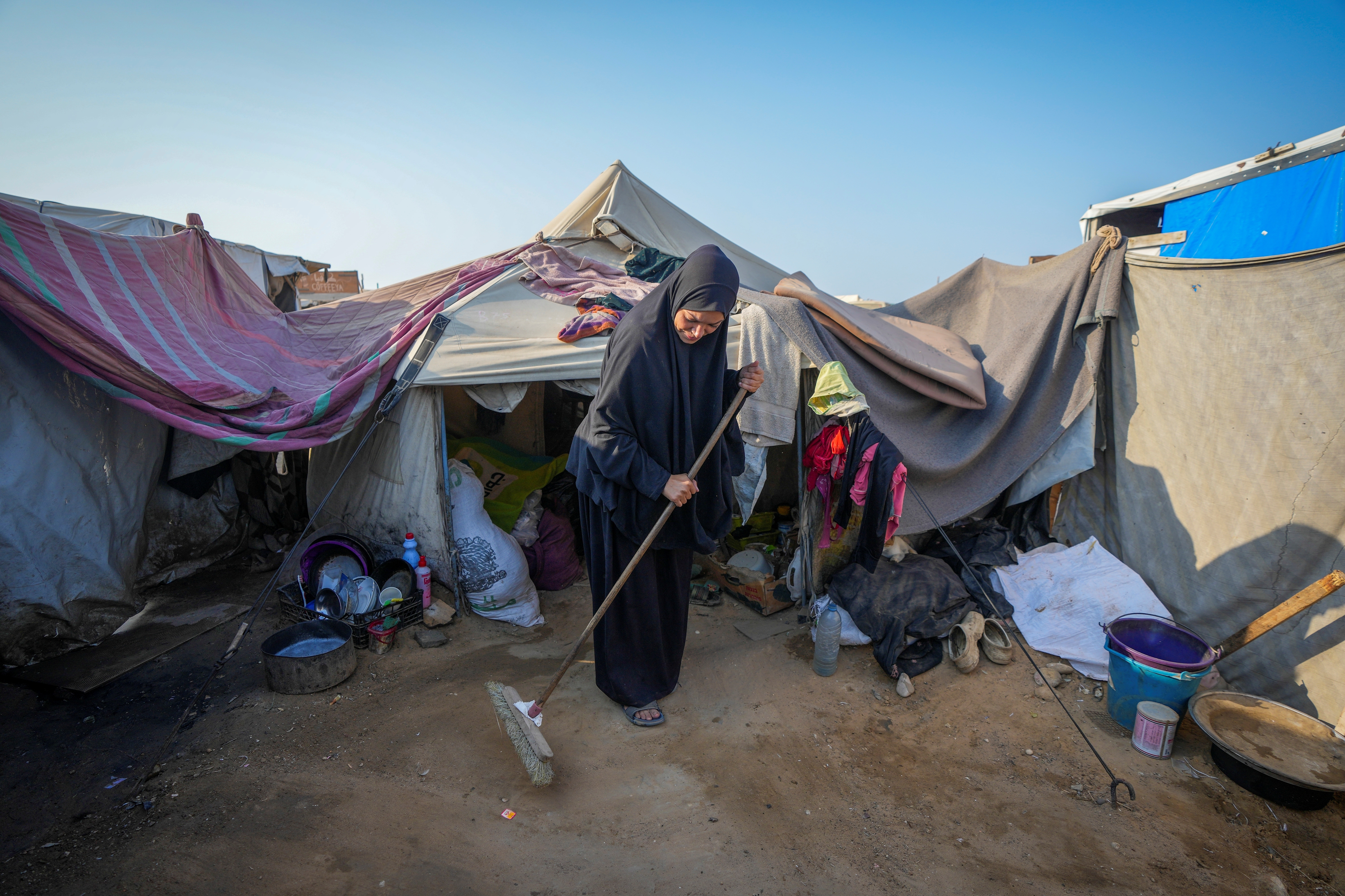 Alaa Hamami cleans outside her tent at a camp.