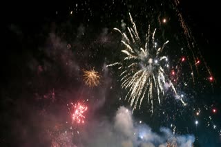 People gather to witness firecrackers that light up the sky as they welcome the New Year at Baga Beachin North Goa