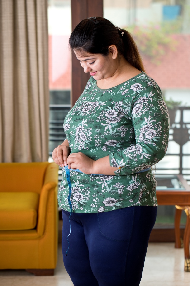 Overweight woman in her 20s measuring her waist