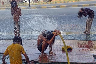 Children take a bath to get relief from the scorching sun on a hot summer day, in Patna on Wednesday, May 22, 2024