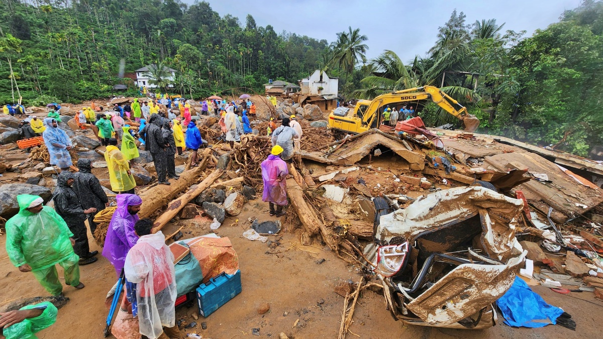 Rescuers and other stand amid debris after landslides hit hilly villages in Wayanad district