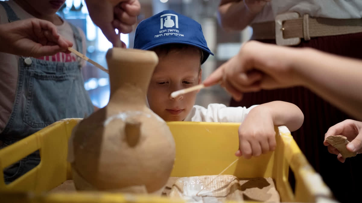 Ariel Heller, 4, helps to glue a broken clay jar during a special tour with his family after he accidentally broke another jar at the Reuben and Edith Hecht Museum in Haifa, Israel, Friday, Aug. 30, 2024. The boy who accidentally broke a rare 3,500-year-old jar in an Israeli museum has been forgiven and invited back, as curators hope to turn the disaster into a teachable moment.