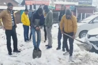 Tourists clear snow from roads