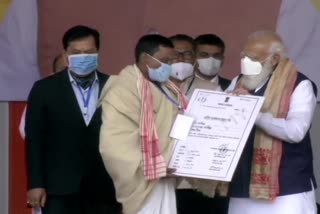 Prime Minister Narendra Modi distributes land allotment certificates to indigenous people, in Sivasagar, Assam