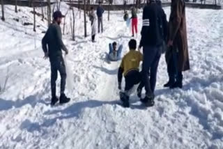 Children sliding through snow covered valley in Kashmir