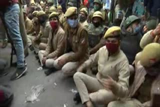 Police officials sit on road in Nangloi to block the area where farmers holding tractor parade have reached