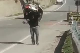 man lifts scooty on his shoulder