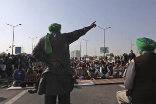 Protesting farmers listen to a speech as they camp on a highway at the Delhi- Uttar Pradesh border