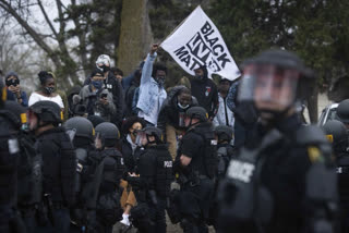 A person confronts a police officer near the site where a family said a man was shot and killed by local law enforcement