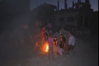 A family from Gaza City huddled around a fire surrounded by the ruins of their home