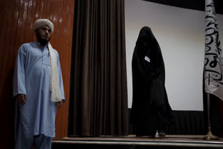 A women walks down from the stage inside an auditorium at Kabul University's education center during a demonstration in support of the Taliban government