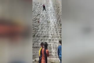 Young Man attempts to climb dam wall in Chikkaballapura  slips and falls  ശ്രീനിവാസ് സാഗർ അണക്കെട്ടിന്‍റെ മതിൽ കയറാൻ ശ്രമിച്ച് യുവാവ്  അണക്കെട്ടിന്‍റെ മതിൽ കയറാൻ ശ്രമിച്ച യുവാവ് കാൽ വഴുതി വീണ് ഗുരുതരമായി പരിക്കേറ്റു  കർണാടകയിലെ ചിക്കബല്ലാപുര ജില്ലയിൽ അണക്കെട്ടിന്‍റെ മതിൽ കയറാൻ ശ്രമിച്ച് യുവാവ്  അണക്കെട്ടിന്‍റെ മതിലിൽ നിന്ന് വീണ യുവാവിന് ഗുരുതര പരിക്ക്