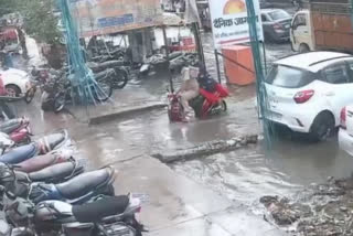 husband wife fell in drain  Aligarh muncipal corporation  couple on scooter fell in drain  couple on scooter swallowed by drain in waterlogged up road in Aligarh  സ്‌കൂട്ടറിൽ സഞ്ചരിച്ച ദമ്പതികൾ തുറന്നിട്ട ഓടയിൽ വീണു  അലിഗഡ് വെള്ളക്കെട്ട് വാഹനം ഓടയിൽ വീണു