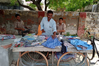 man sells clothes on handcart with two gunners in etah
