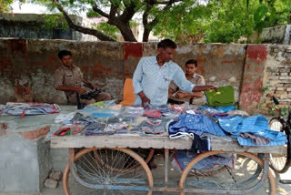 Vendor sells clothes on his cart along with two policemen