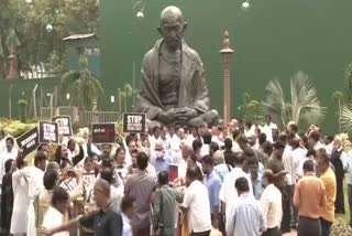 Opposition MPs protest in front of the Mahatma Gandhi statue