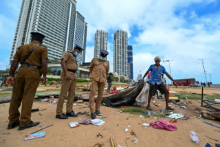 Policemen watch as demonstrators dismantle an anti-government protest camp near the Presidential Secretariat in Colombo on August 12, 2022. (Photo by ISHARA S. KODIKARA / AFP)