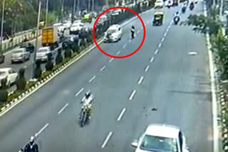 car hit young woman  car hit young woman crossing the road  Woman narrow escape from road accident  ಅವಸರವೇ ಅಪಘಾತಕ್ಕೆ ಕಾರಣ  ಡಿವೈಡರ್​ ಮೇಲೆ ಹಾರಿ ಬಿದ್ದ ಯುವತಿ  ರಸ್ತೆ ದಾಟುವಾಗ ಯುವತಿಗೆ ಕಾರ್​ ಡಿಕ್ಕಿ  ಸಿಸಿಟಿವಿಯಲ್ಲಿ ಅಪಘಾತ ದೃಶ್ಯ ಸೆರೆ