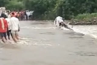 Video: Man tries to cross a flooded bridge, but escapes in the nick of time