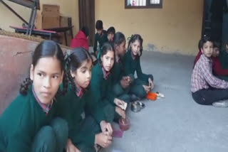 Students eating on the floor in a school in Batala