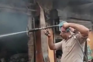 सिवान में किराना दुकान में लगी आग को बुझाता कर्मी