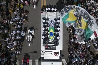 The casket of late Brazilian soccer great Pele is draped in the Brazilian and Santos FC soccer club flags as his remains are transported from Vila Belmiro stadium, where he laid in state, to the cemetery during his funeral procession in Santos, Brazil, Tuesday, Jan. 3, 2023.