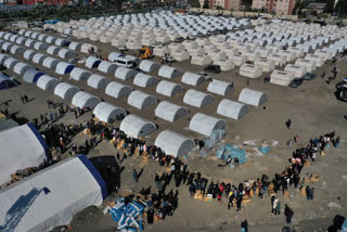 People who lost their houses in the devastating earthquake, lineup to receive aid supplies at a makeshift camp, in Iskenderun city, southern Turkey, Tuesday, Feb. 14, 2023. A convoy of 11 trucks from a United Nations agency crossed into northern Syria from Turkey on Tuesday, just hours after the U.N. and Syrian government reached an agreement to temporarily authorize two new border crossings into the rebel enclave. (AP Photo/Hussein Malla)