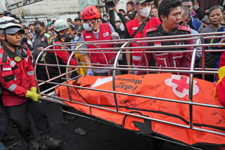 Rescuers recover the body of a victim from a neighborhood affected by a fuel depot fire in Jakarta, Indonesia, Saturday, March 4, 2023. A large fire broke out at the fuel storage depot in Indonesia's capital Friday, killing multiple people, injuring dozens of others and forcing the evacuation of thousands of nearby residents after spreading to their neighborhood, officials said. (AP Photo/Tatan Syuflana)