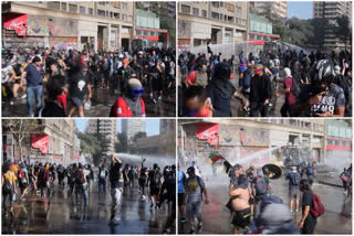 Tear gas amidst protesters throwing rocks at a water cannon truck,