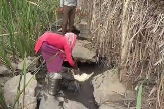 woman washes clothes in drain water