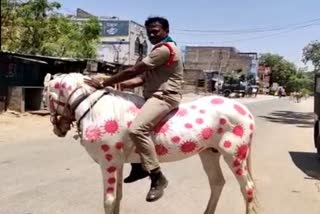 Sub Inspector rides a horse painted with images of  corona virus