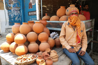 मिट्टी के घड़े न बिकने से मायूस बैठा कुम्हार.