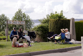 In this photo taken May 17, 2020, de Rham family members from the U.S. and Canada visit at the border between the countries in Peace Arch Park, in Blaine, Washington.