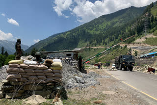 Indian paramilitary soldiers keep guard as Indian army convoy moves on the Srinagar- Ladakh highway on Thursday