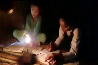 Children studying in the light of lamps