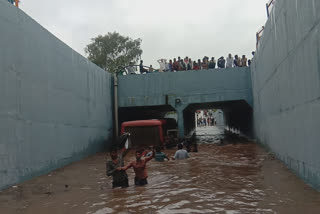 State transport bus  Bus pulled by proclainer  Waterlogged bridge  Rajkot  Gujarat  രാജ്കോട്ട്  ഗുജറാത്ത്  വെള്ളക്കെട്ട്  ജെസിബി