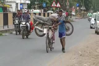 man-carrying-a-bike-on-a-bicycle-in-damoh