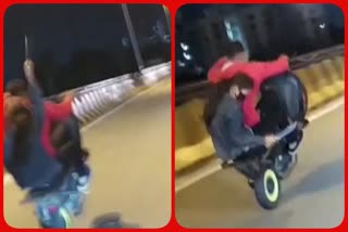 A Youth Stunts with Bike Wheeling, Girl Holds a Sword Sitting with him in the Bike