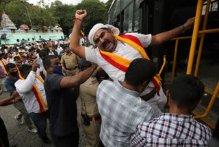 Indian policemen detain a protester during a protest against farm bills in Bengaluru