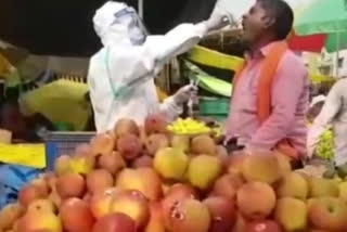 फल विक्रेता की थर्मल स्क्रीनिंग करते स्वास्थ्य कर्मी.