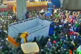 Farmers use a tractor to remove a truck placed as a barricade to stop them from entering Delhi